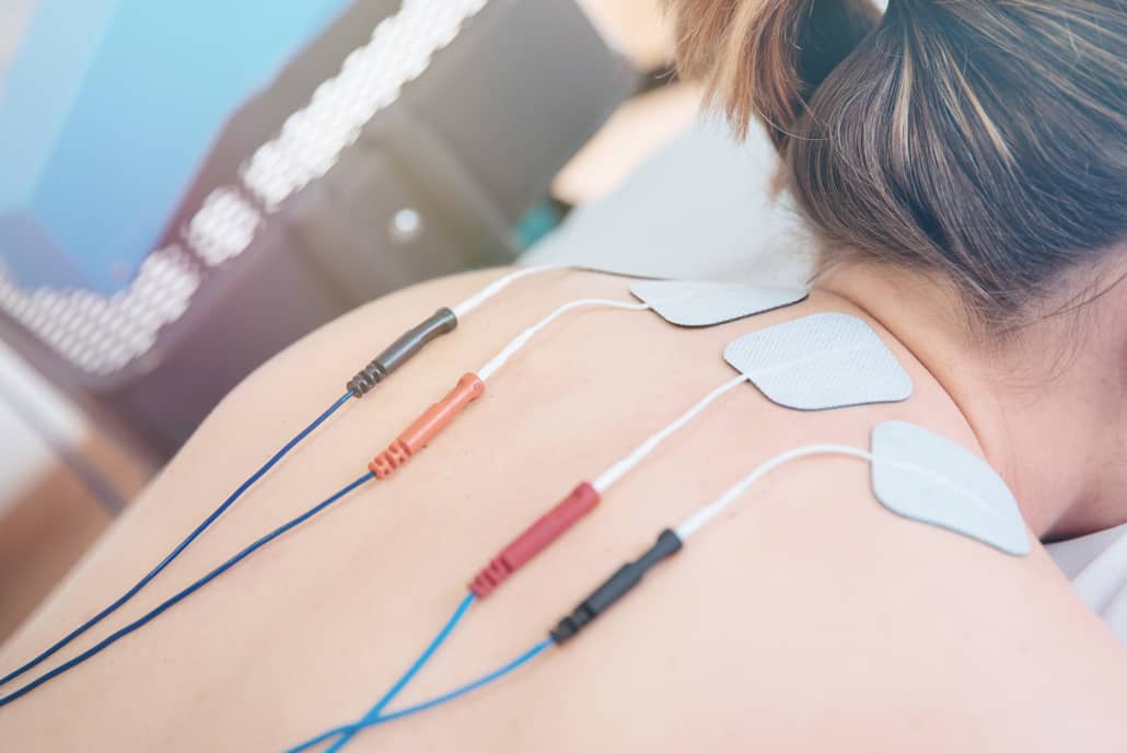 Physical therapist positioning electrodes for high back muscle treatment