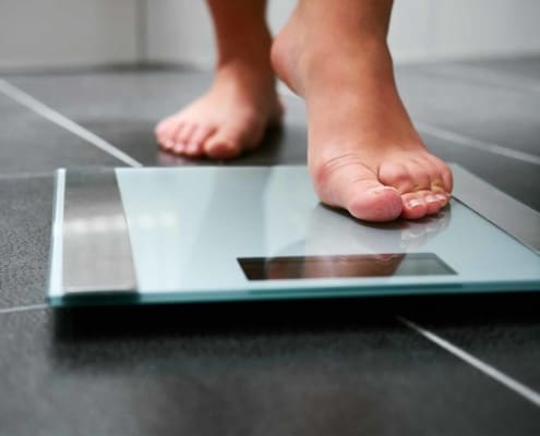 Close up view of woman stepping on a scale