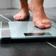 Close up view of woman stepping on a scale
