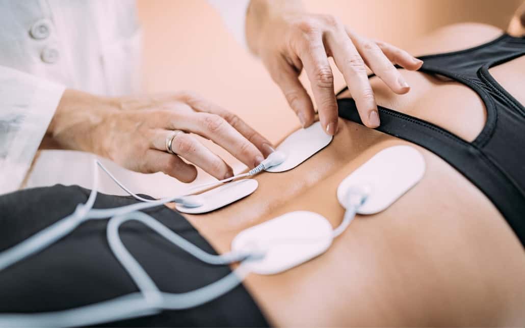 Image of a medical profession using an electrical nerve stimulator on a patient.