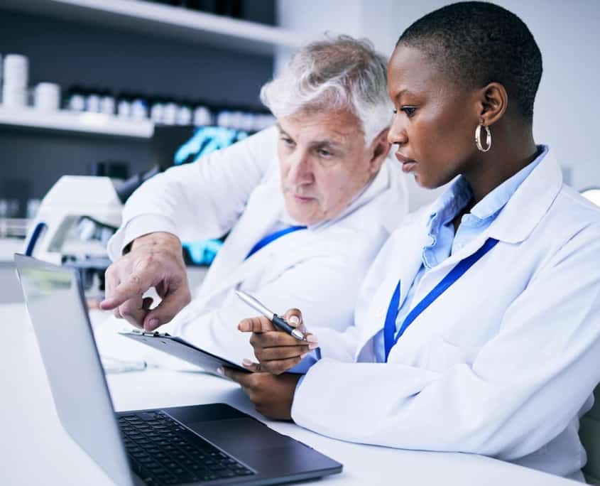 Side view of two doctors looking at a laptop