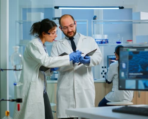 Side view of two medical professionals in lab coats looking at data