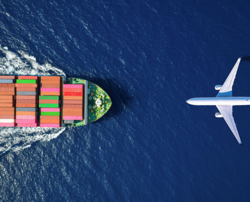 Aerial overhead view of a large container ship and airplane traveling over the ocean